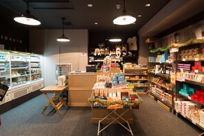 Interior de una tienda con mostrador de exhibición, estanterías llenas de productos y una sección refrigerada.
