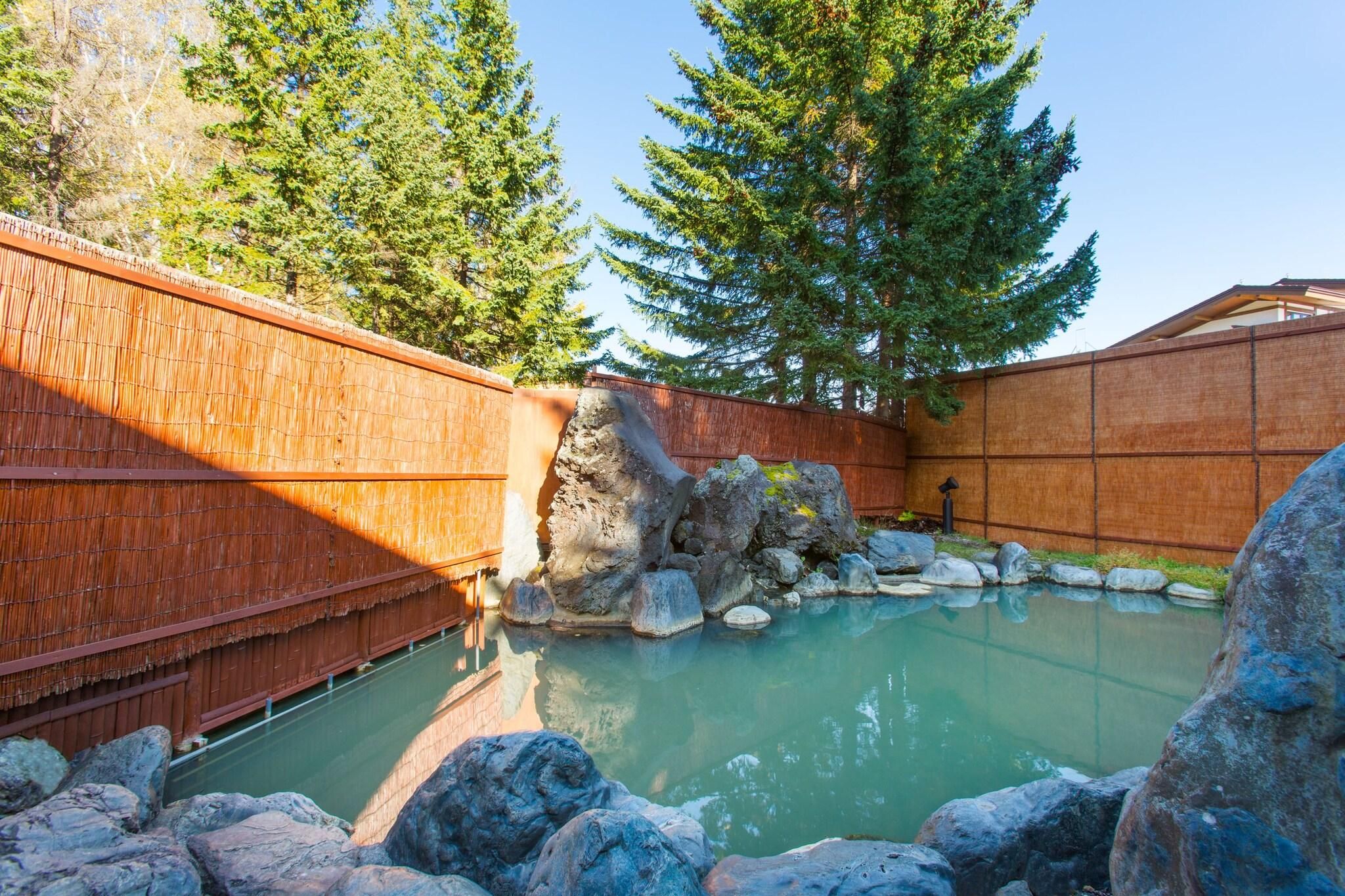 A wooden fence, a rock formation, and a clear pool.
