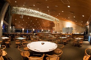 A spacious restaurant with multiple dining tables and chairs, a high ceiling with hanging decorations, and a bar area. - The Green Leaf Niseko Village, Tapestry Collection (Niseko)