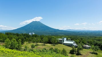 A mountain with a small building in the foreground and a larger building in the background.