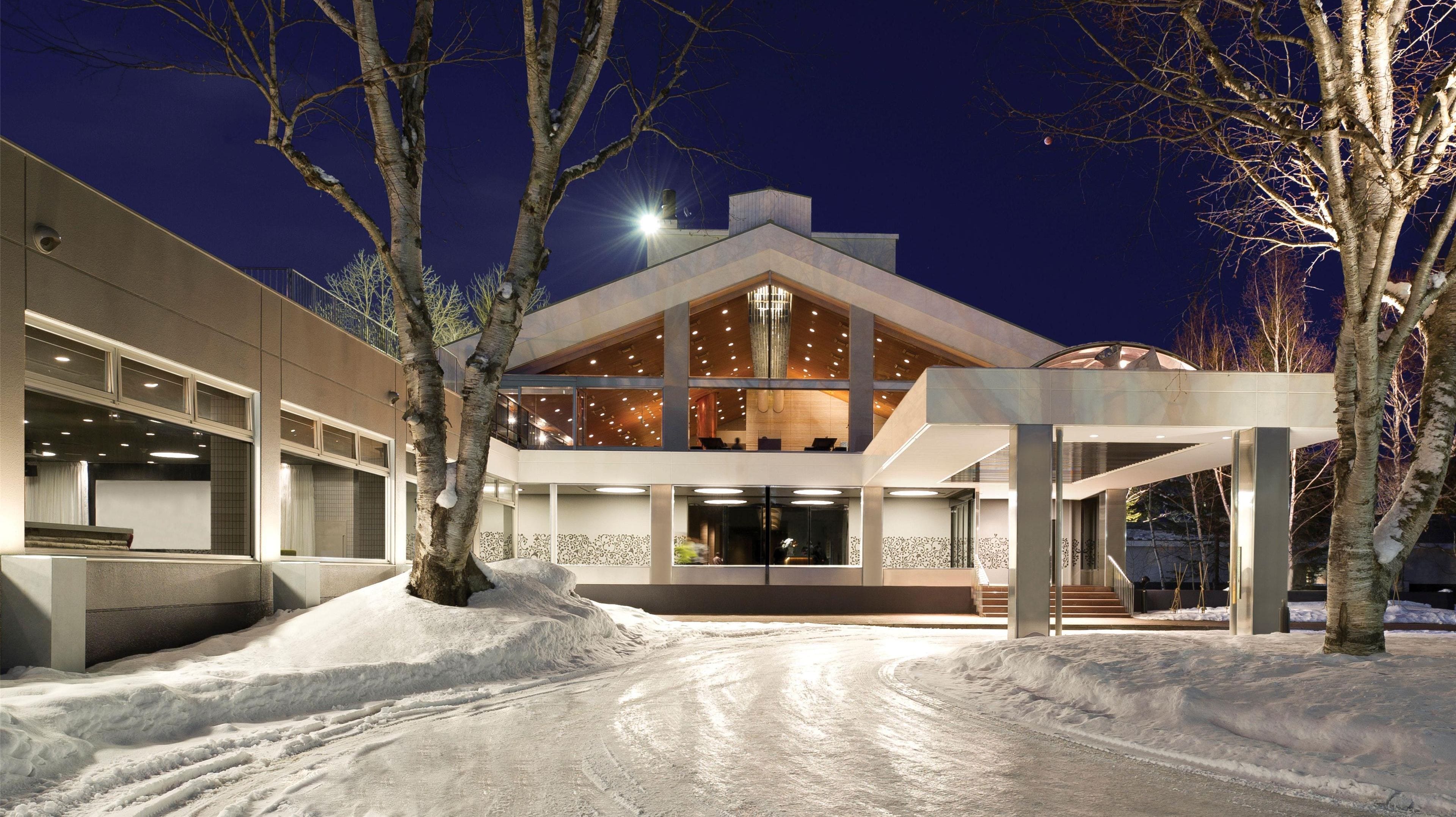 A modern building with a large entrance, multiple windows, and a snow-covered ground.