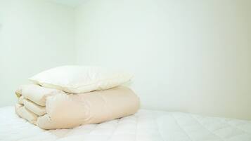 A neatly made bed with a white quilt and several beige pillows.