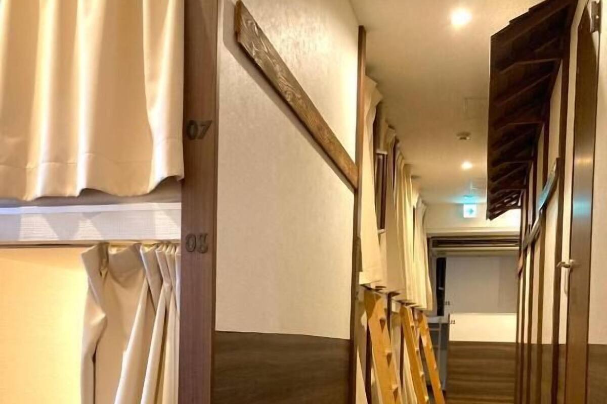 Corredor de hotel com piso de madeira, moldura de porta em madeira e escada de madeira.