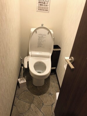 Un baño pequeño con inodoro, bidé y un cartel en japonés.