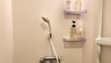 A shower with a handheld showerhead and a handheld shower attachment. There are two shelves with bottles of toiletries.