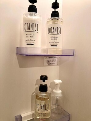 A bathroom shelf with three bottles of Botanist products: two bottles of Botanical Treatment and one bottle of Botanical Body Soap.