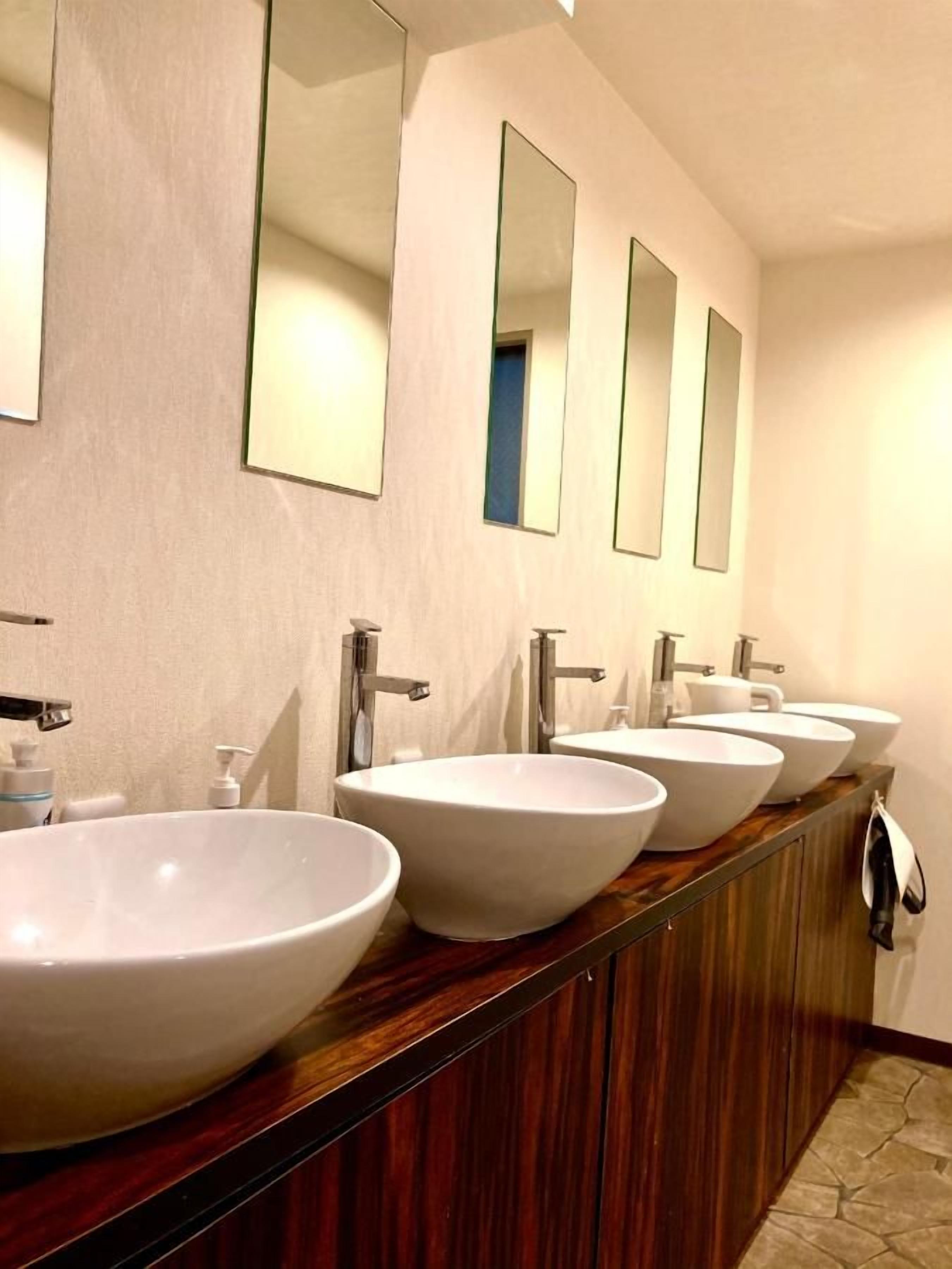 A bathroom with four white sinks and mirrors on the wall.