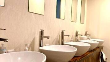 A bathroom with four white sinks and mirrors on the wall.
