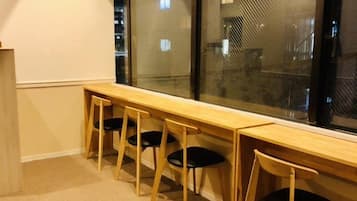 A room with a long wooden table and four chairs, a large window with a view of the city, and carpeted flooring.