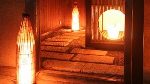 Perinteinen japanilainen sisustus, jossa on tatamimatto, matala puukatto ja valaistu paperilyhty.