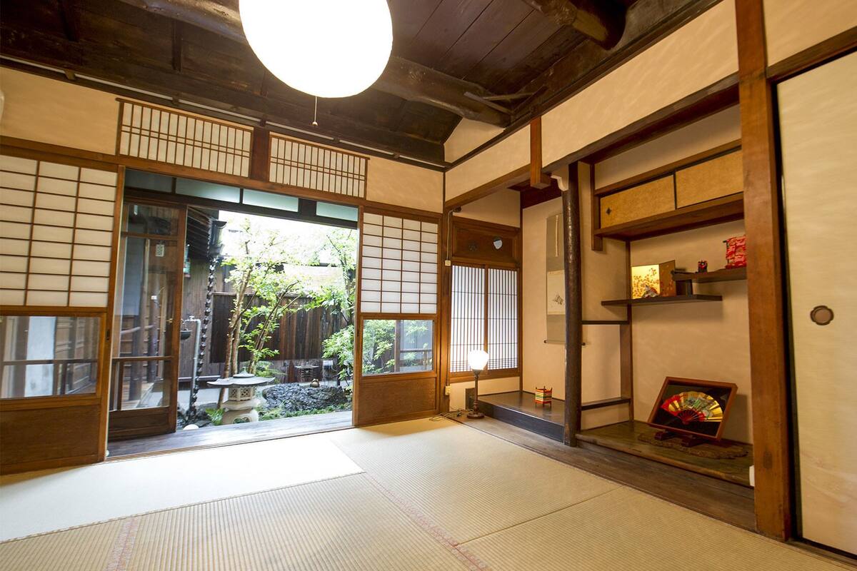 A traditional Japanese room with tatami flooring, sliding doors, and a view of a garden.