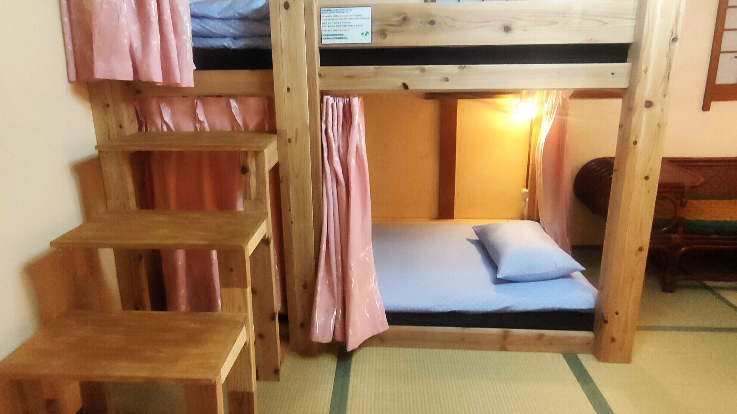 Habitación con literas de madera, una cama individual con almohada y una mesita pequeña.