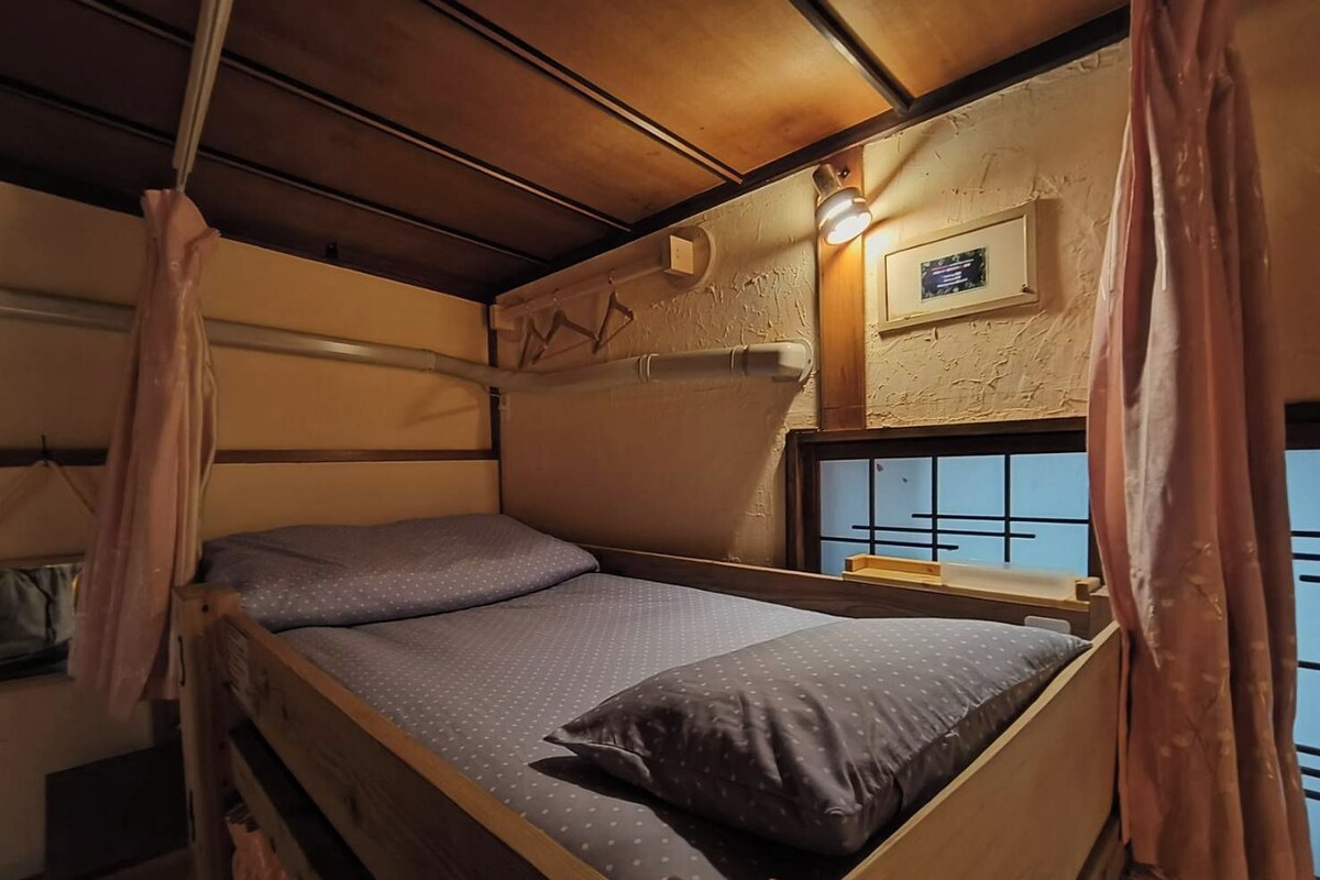 A bunk bed with a window, wooden headboard, and a small shelf with a framed item.