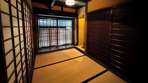 Ein traditioneller japanischer Raum mit Tatami-Boden, Schiebetüren und Blick durch einen Shoji-Bildschirm.