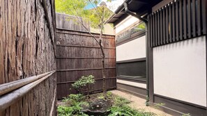 A traditional Japanese garden with a wooden fence, a small pond, and a building with a shoji screen. - Rinn Shijo Machiya (Kyoto)