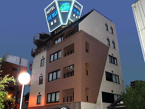 Ein mehrstöckiges Hotel mit einem auffälligen Schild, das 'HOTEL LIVE MAX' und 'HOTEL GROUP' bewirbt.