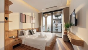 A modern bedroom with a wooden bed, bedside tables, a TV, and a balcony view. - GRAND LUX by BRIO (Da Nang)