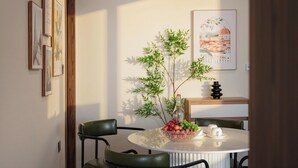 A dining area with a round table, chairs, a vase with flowers, and framed artwork on the wall. - GRAND LUX by BRIO (Da Nang)