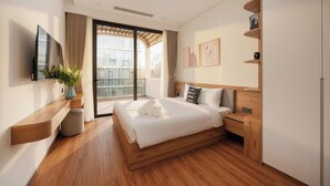 A modern hotel room with a large bed, a TV, a wooden nightstand, and a view of the city. - GRAND LUX by BRIO (Da Nang)
