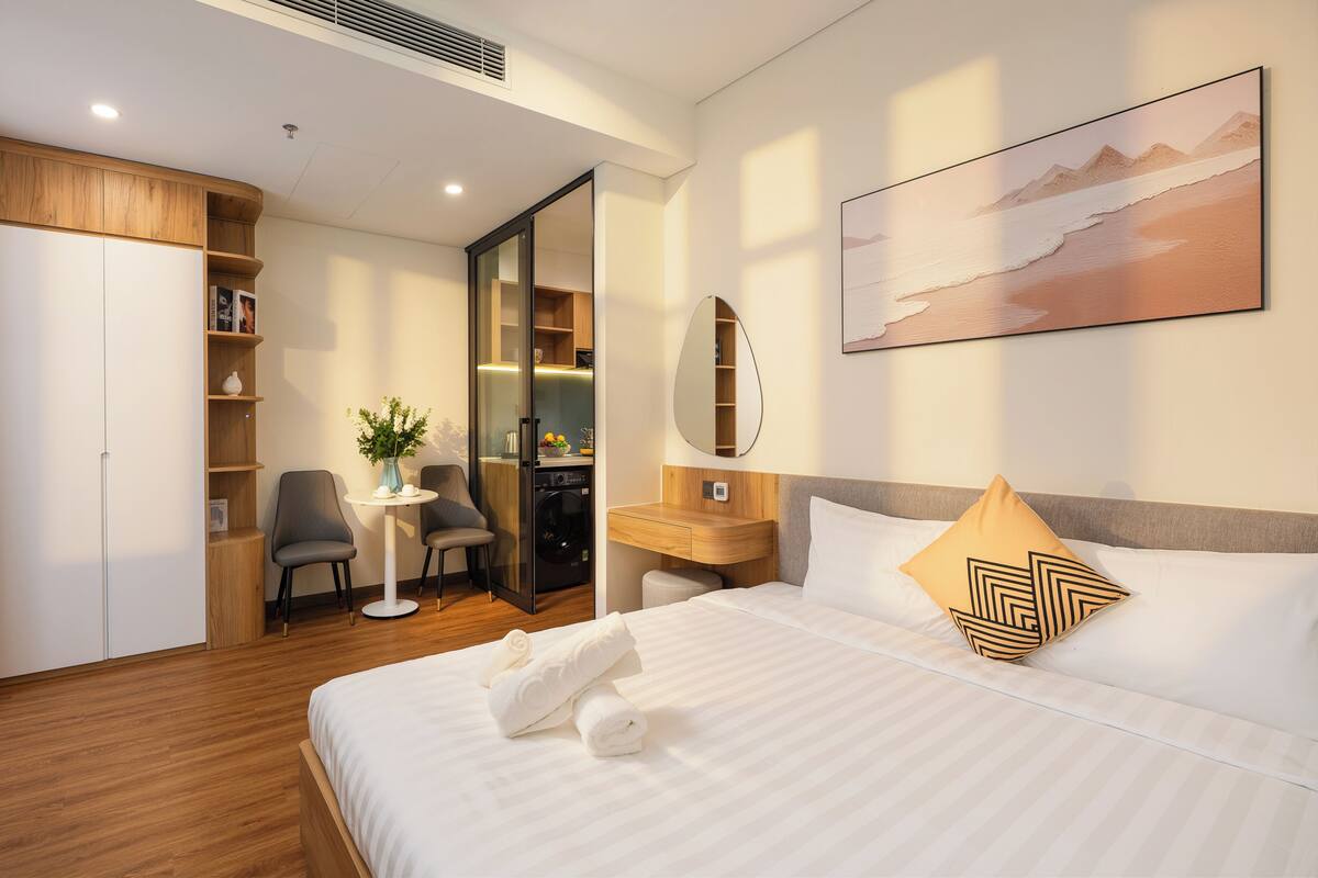 Una habitación de hotel con cama, escritorio, silla, armario y baño.