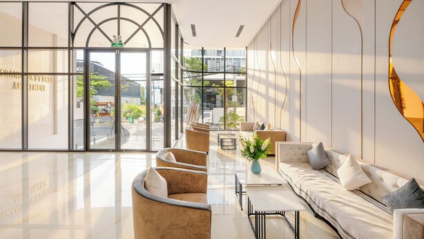 A modern hotel lobby with a glass entrance, seating areas, and a view of the outdoors. - GRAND LUX by BRIO (Da Nang)