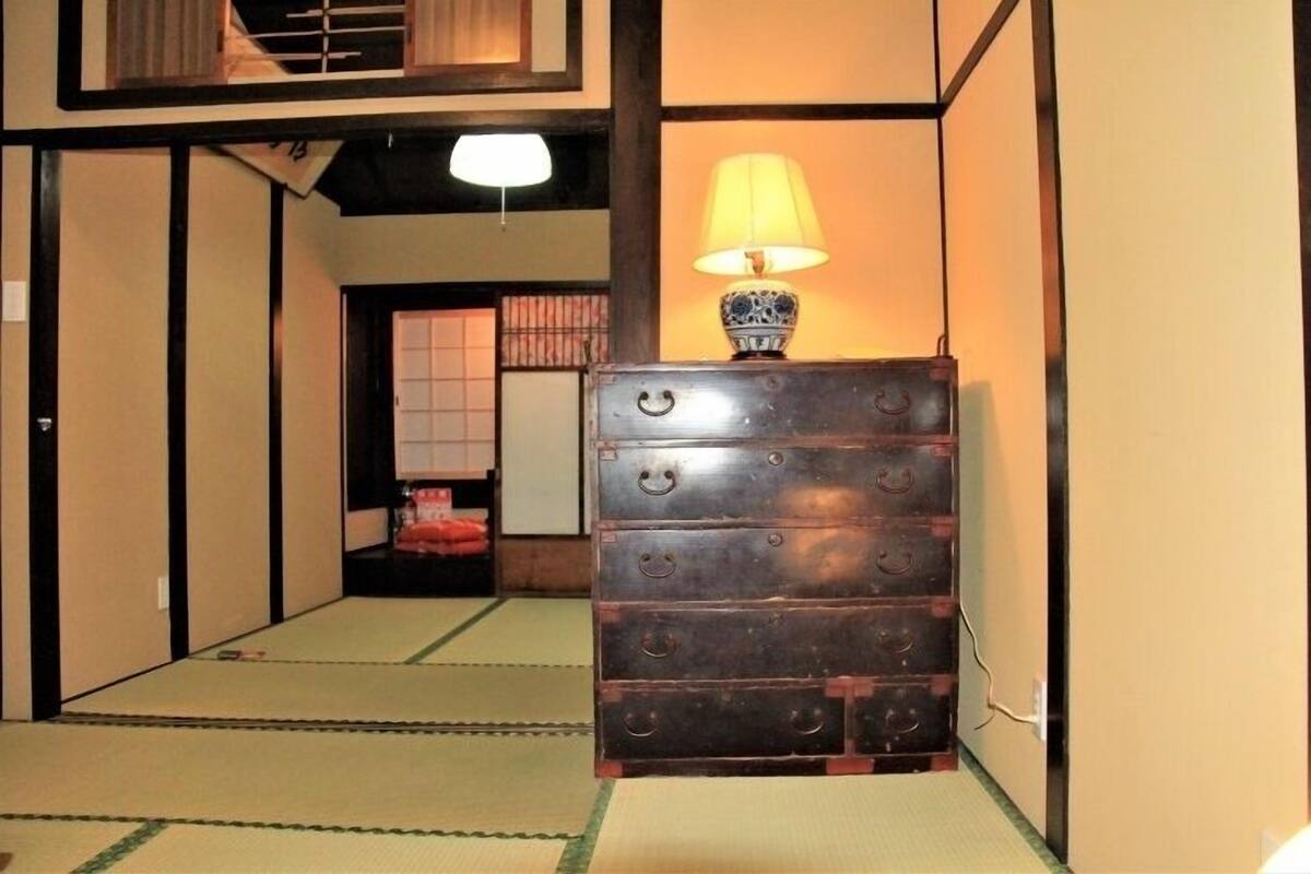 Um quarto japonês tradicional com tatames, um armário de madeira e uma luminária.