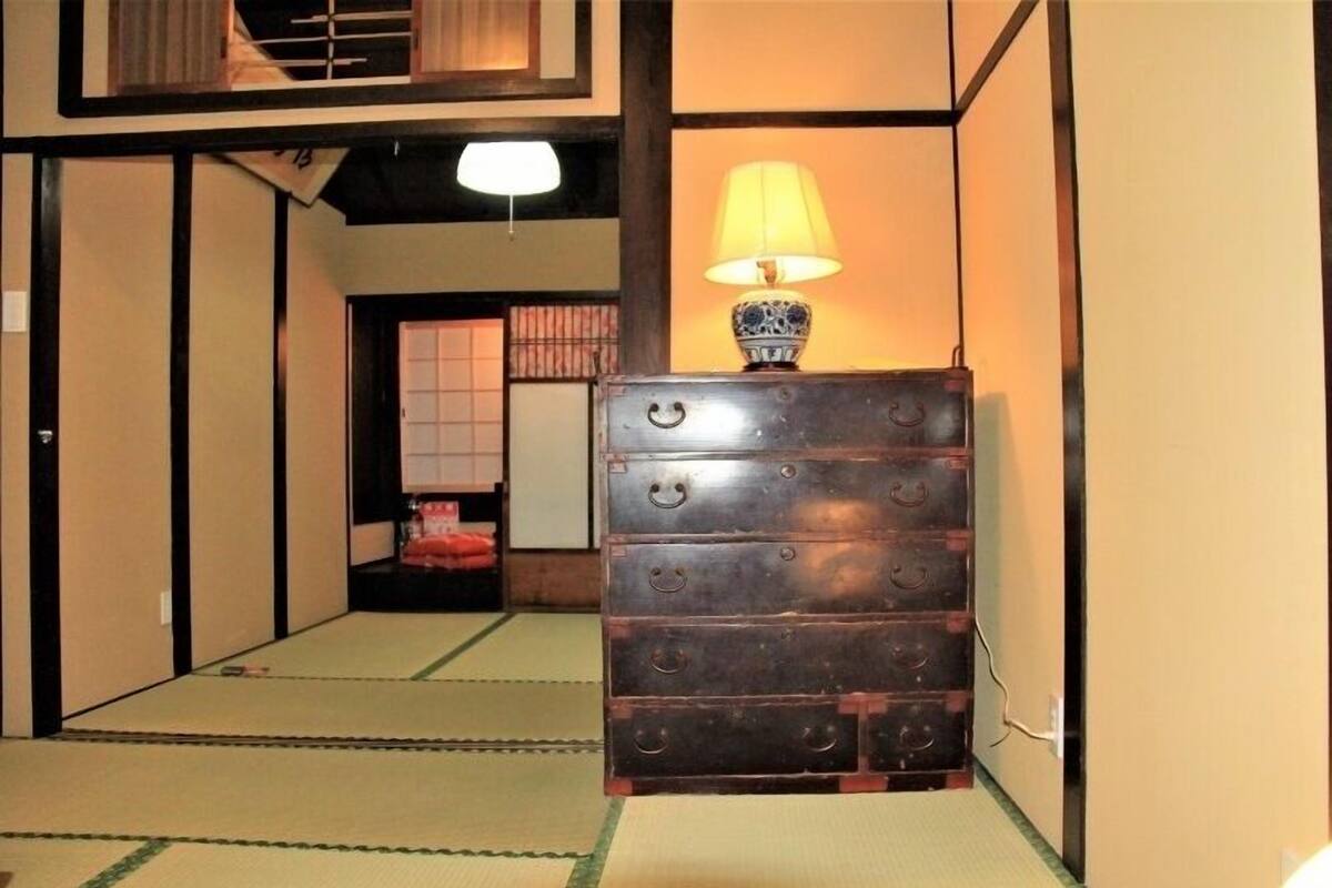 Um quarto japonês tradicional com chão de tatame, um armário de madeira com carinhas sorridentes e uma luminária.