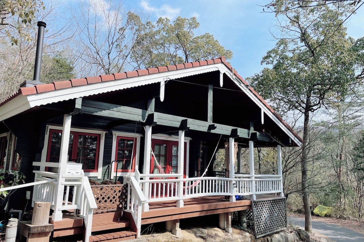 A cabin with a porch, wooden steps, and a chimney.