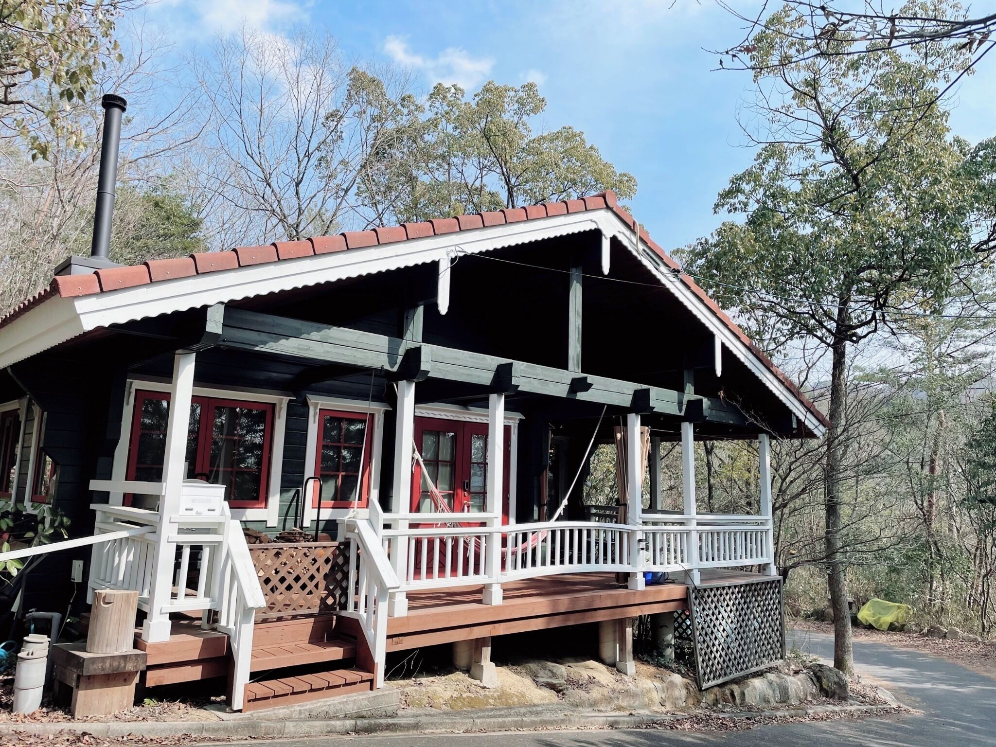 Een chalet met een veranda, houten trappen en een schoorsteen.