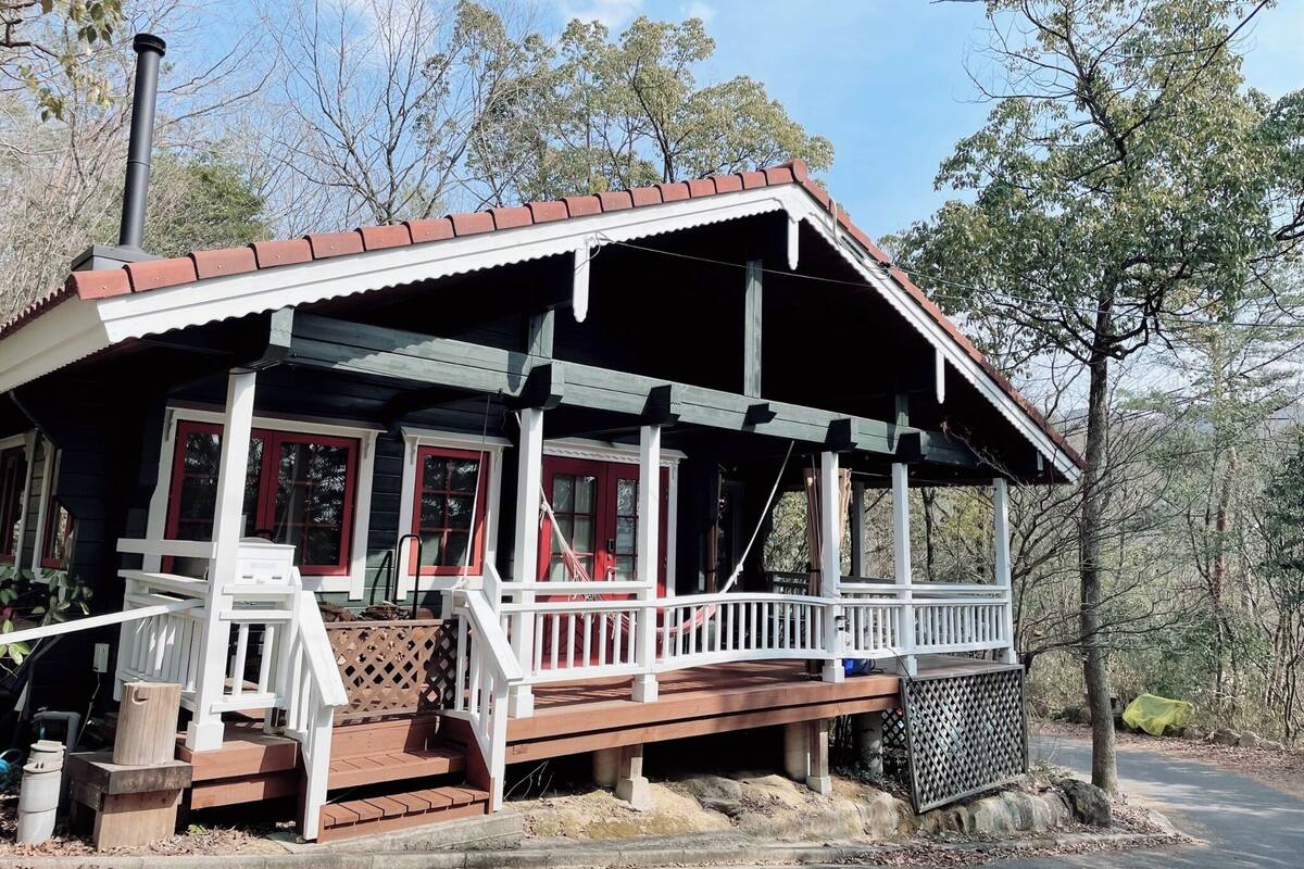 A cabin with a porch, wooden steps, and a chimney.