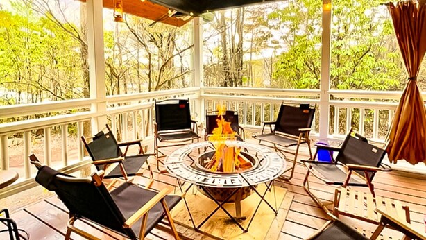 A covered outdoor seating area with a fire pit, surrounded by chairs and a table. - Asobi No Cottage Hatsukaichi (Hatsukaichi)