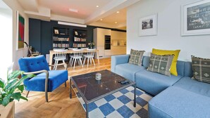 A modern living room with a blue sofa, a coffee table, and a bookshelf.