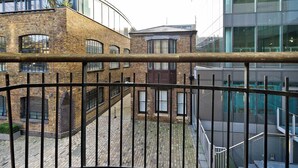 A courtyard with a brick building, a modern glass structure, and a metal railing.