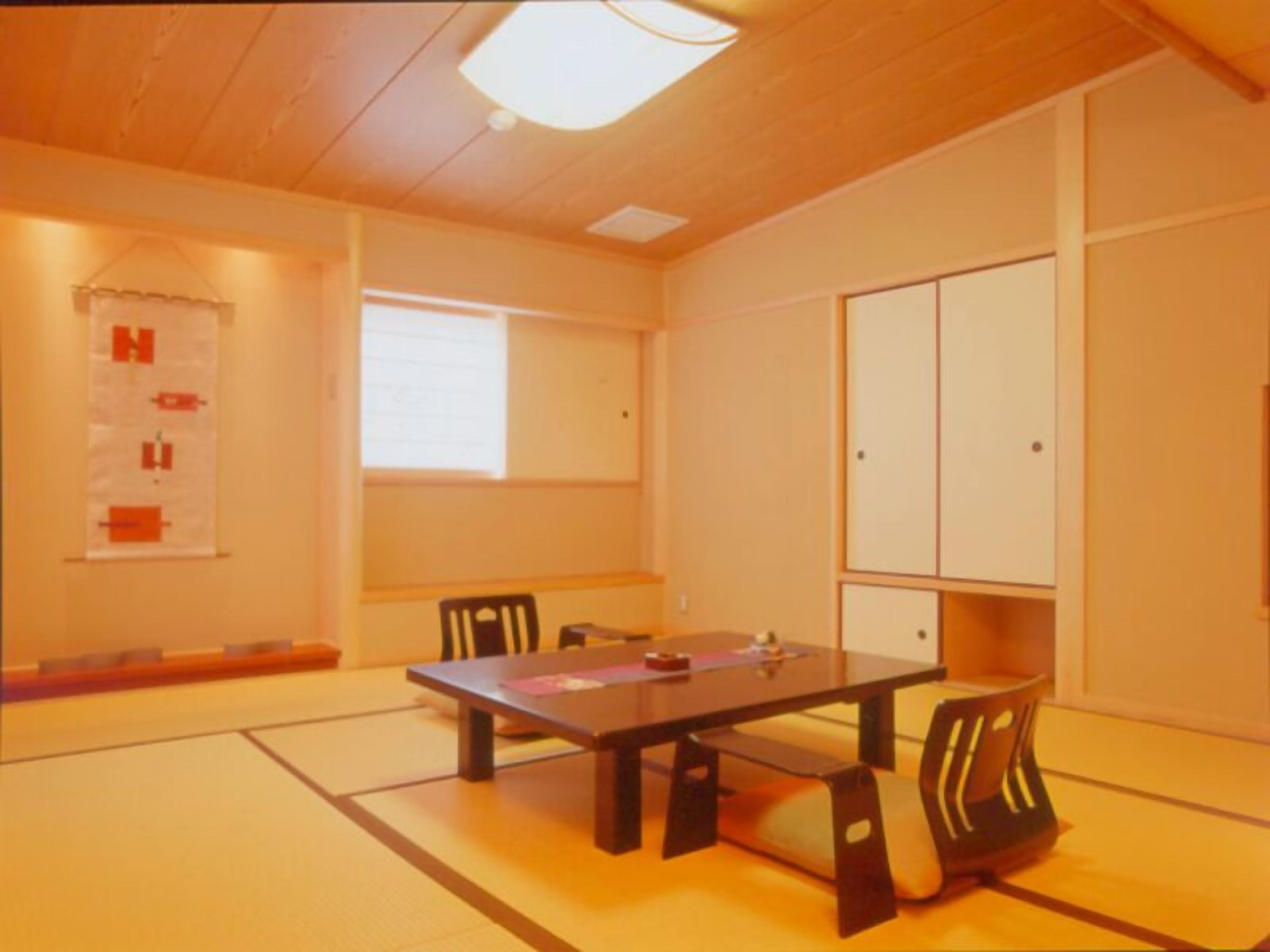 Ein traditioneller japanischer Raum mit Tatami-Böden, einem niedrigen Tisch, vier Stühlen, einem Shoji-Bildschirm und Schiebetüren.