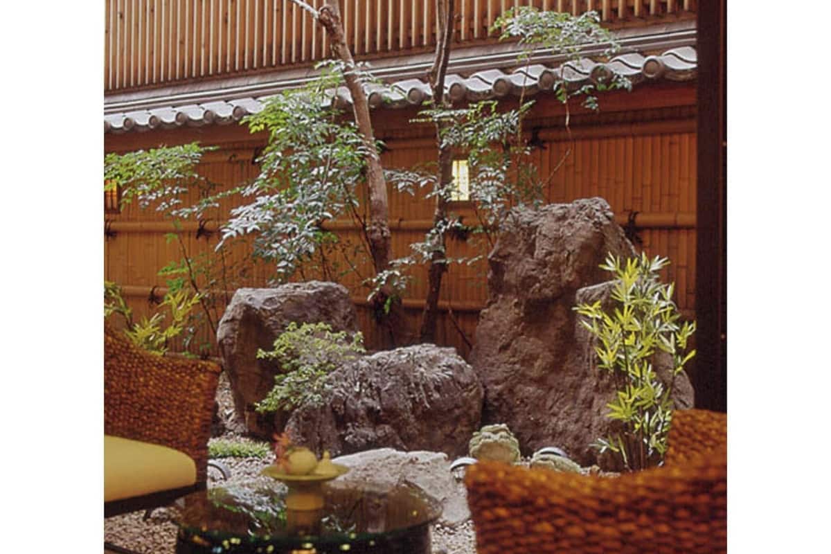 Una habitación japonesa tradicional con suelo de tatami, una mesa de madera baja y un jardín de rocas.