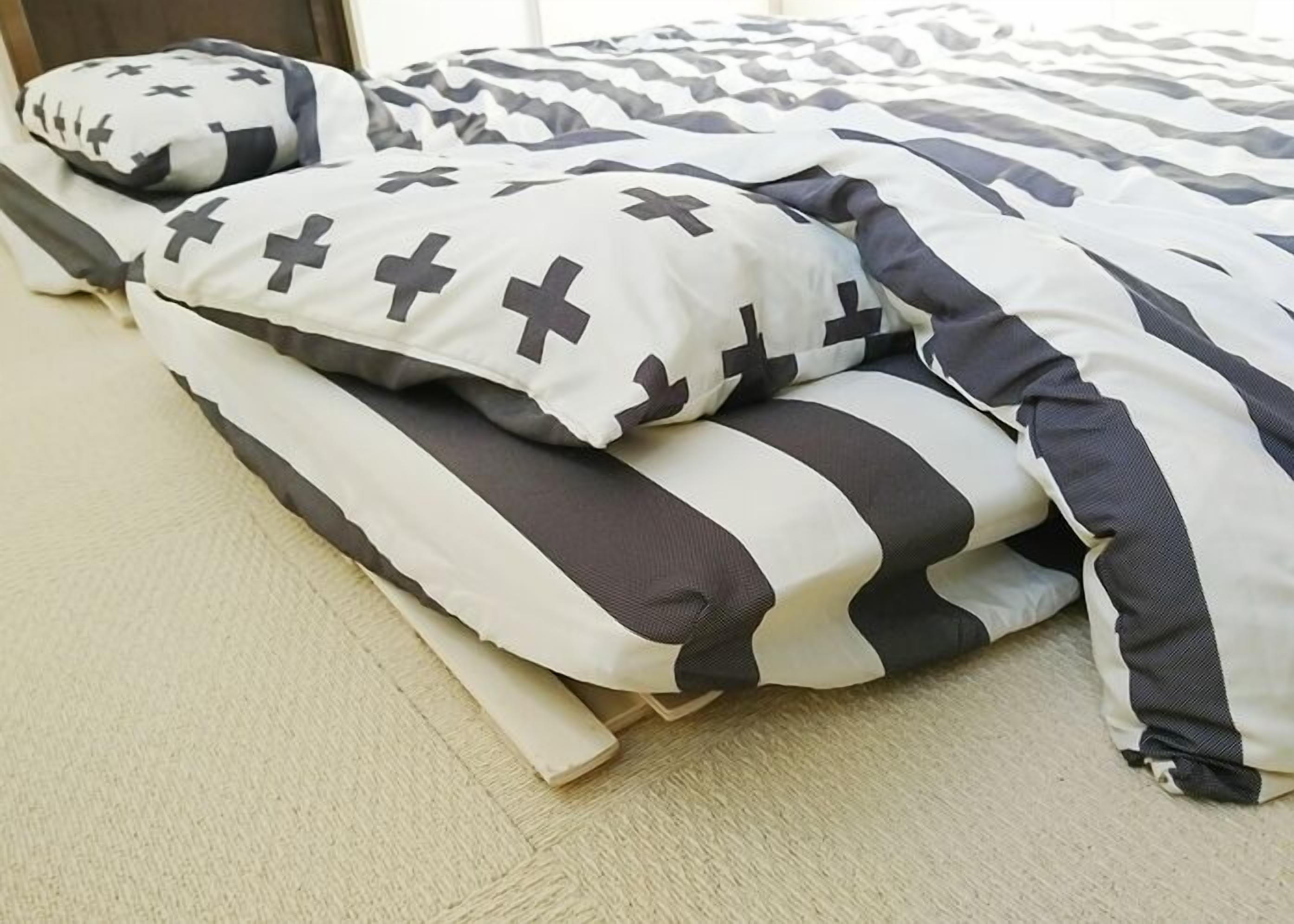 A bed with a striped bedspread and pillows with cross patterns.