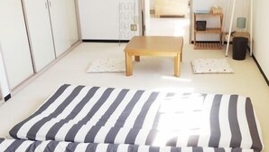 Een kamer met een bed, een klein houten tafeltje en een kledingkast.
