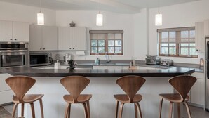 Een moderne keuken met een centraal eiland, roestvrijstalen apparatuur en hanglampen.