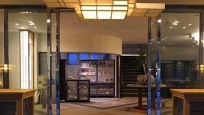 Un hall de hotel con alfombra estampada, puertas de cristal y mostrador de recepción.
