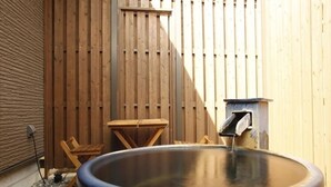 Un jacuzzi con valla de madera, una mesa y una silla en un patio trasero.