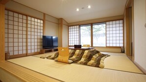 Una habitación con esterillas de tatami, un televisor, un sofá y una mesa.