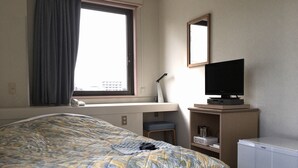 A hotel room with a bed, a television, a desk with a lamp, a window with curtains, and a radiator. - Business Hotel Century (Iizuka)