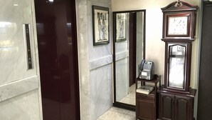 An elevator, a telephone, and a wall-mounted clock in a lobby area. - Business Hotel Century (Iizuka)