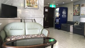 A lobby with a sofa, a glass-top table, a coffee vending machine, a clock, and a poster on the wall. - Business Hotel Century (Iizuka)