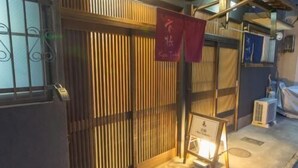 Una habitación con puerta corredera tipo shoji, una mesita con un letrero y una ventana con barrotes.