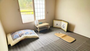 Una habitación pequeña con una cama, un escritorio, una silla, un ventanal y un tapete en el suelo.