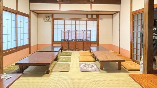 Una habitación japonesa tradicional con esteras de tatami, mesas bajas y puertas correderas.