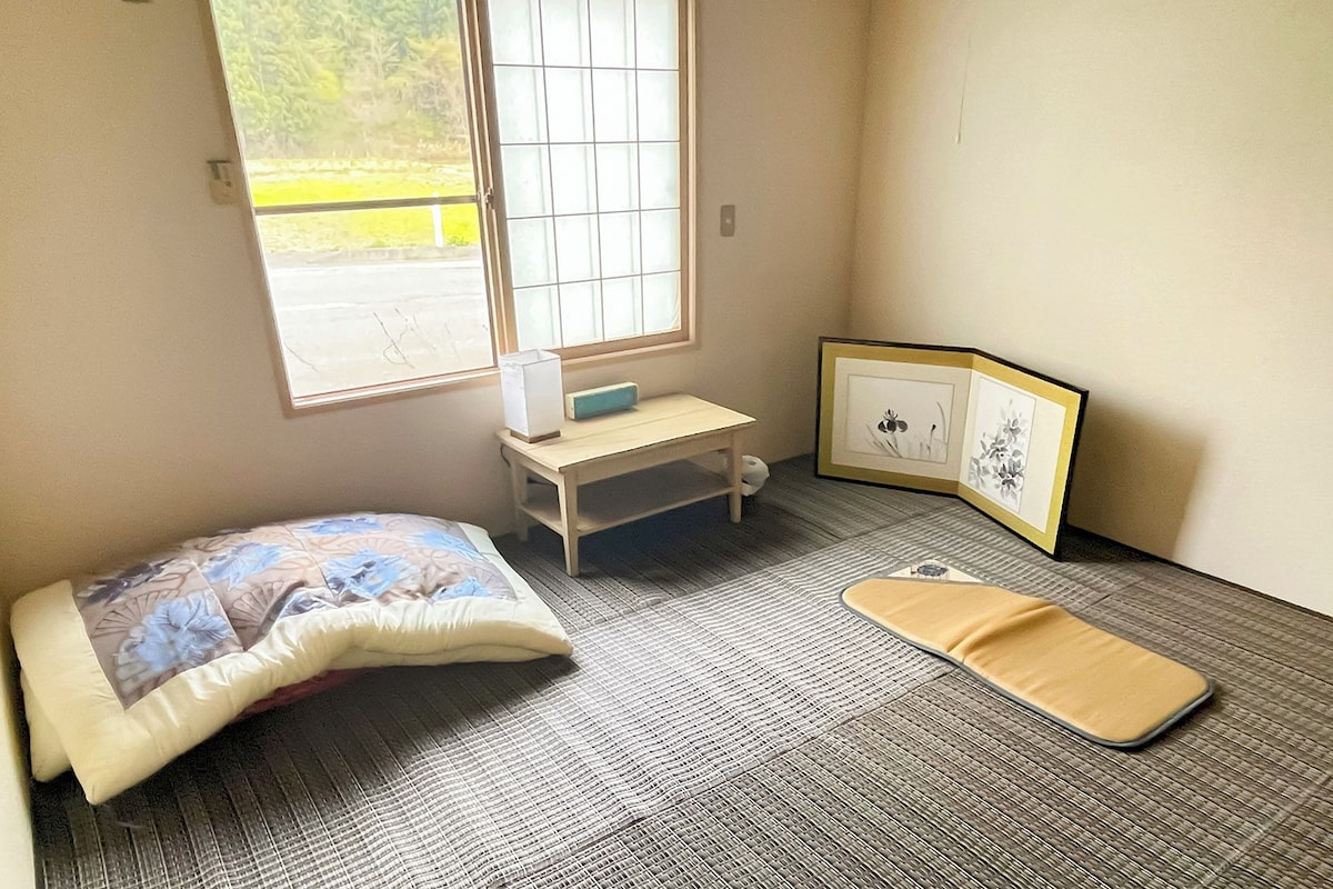 Une petite pièce comprenant un lit, un bureau, une chaise, une fenêtre et un tapis sur le sol.