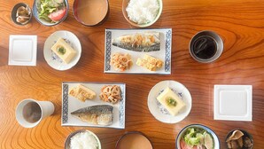 Una mesa de madera con varios platos, incluyendo pescado, arroz y verduras.