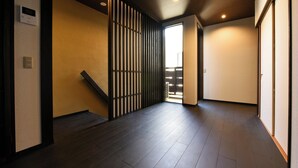 A hallway with a dark wooden floor, a sliding door, and a view of a balcony. - Shibashi Umeyacho (Kyoto)